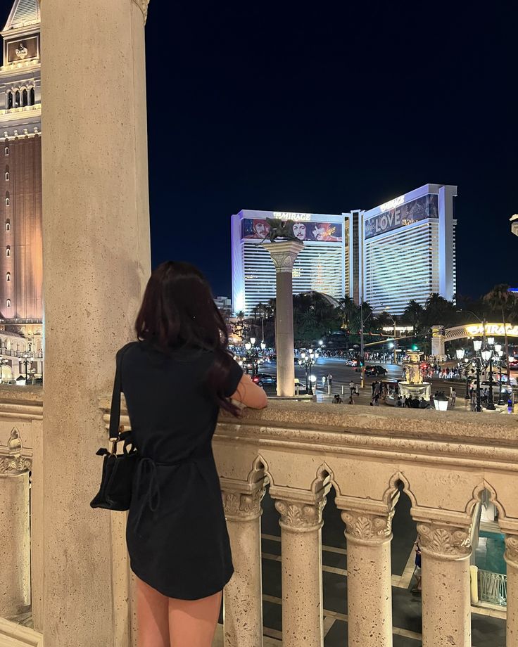 a woman is standing on the balcony looking at the las vegas hotel and casino towers