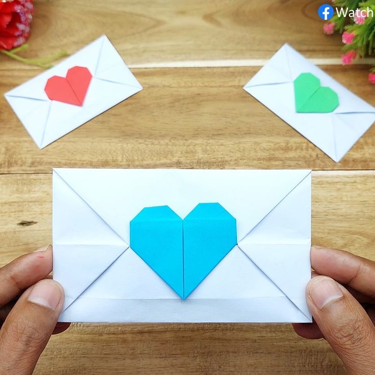 someone is holding an origami envelope with two hearts on it and one in the middle