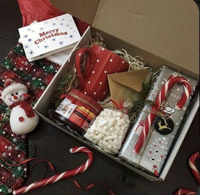 an open christmas gift box filled with candy canes, marshmallows and candies