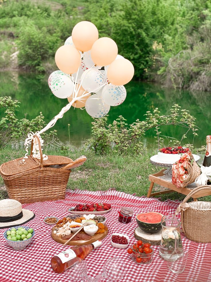 a picnic table with balloons and food on it