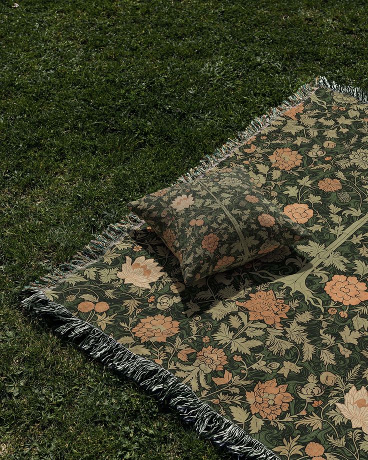 a blanket and pillow laying on the ground with grass in the backgroung