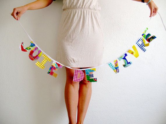 a woman standing in front of a white wall holding a banner that says happy birthday