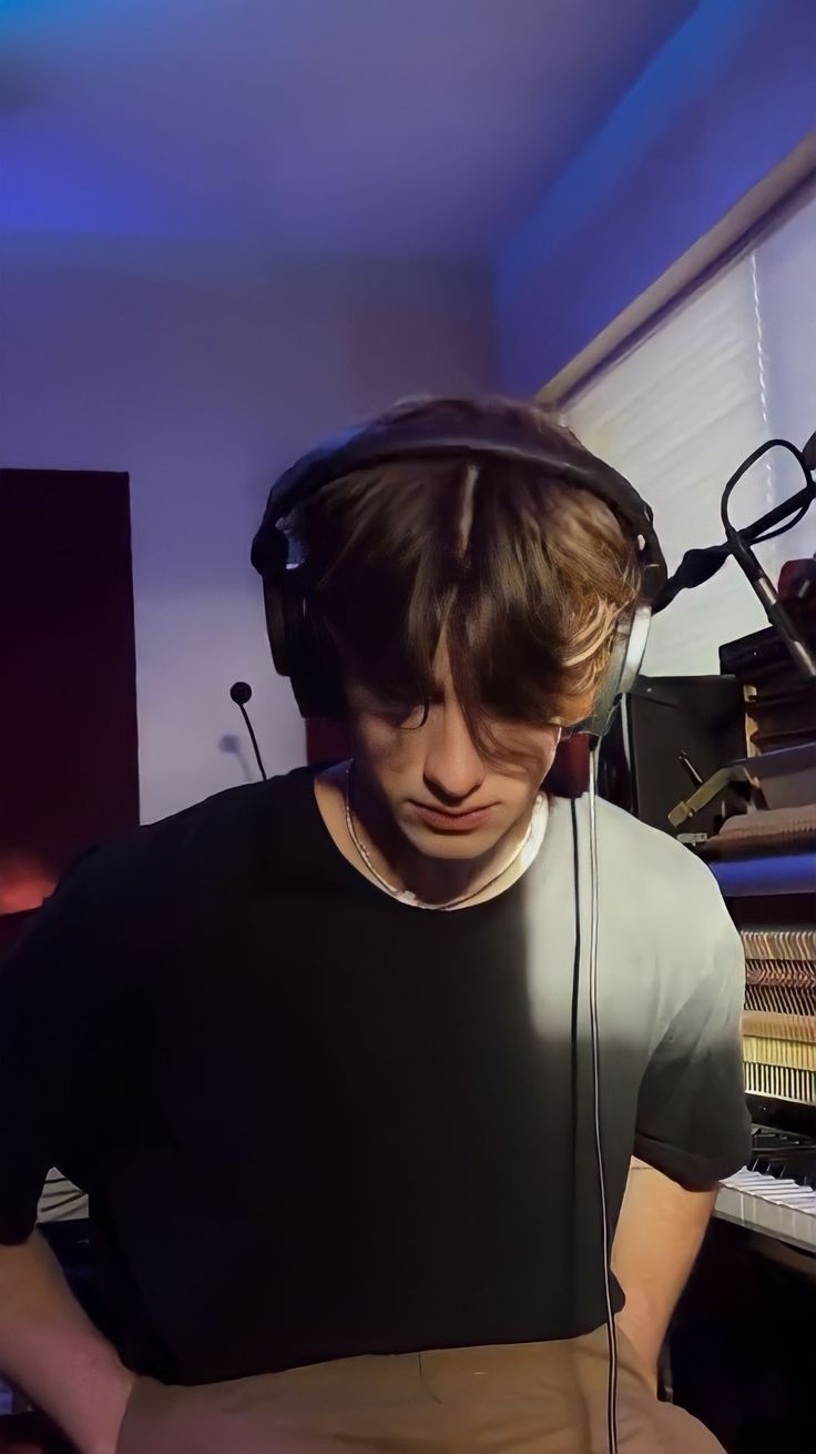 a young man wearing headphones in front of a piano