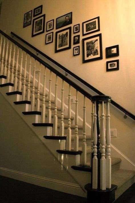 a staircase with pictures on the wall and framed photos on the wall above it, along with black and white stairs