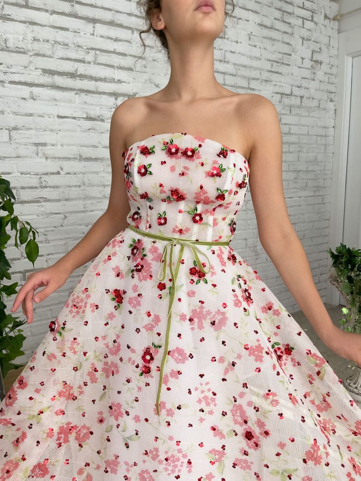 Enjoy long days and short nights in the Tulip Fields Gown. With a mesh-net fabric and a straight neckline, you can feel the warm summer wind on your skin. Embroidered with miniature flowers and crystal leaves so you can live in a blossoming garden... Feminine Spring Gown With Floral Embroidery, Feminine Floral Embroidered Gown For Spring, Organza Gown For Garden Party, Floral Embellished Prom Gown For Summer, Organza Dress With Floral Applique For Garden Party, Floral Applique Organza Dress For Garden Party, Summer Tulle Gown With Floral Embroidery, Spring Gown With Floral Embroidery And Sweetheart Neckline, Spring Floral Applique Gown