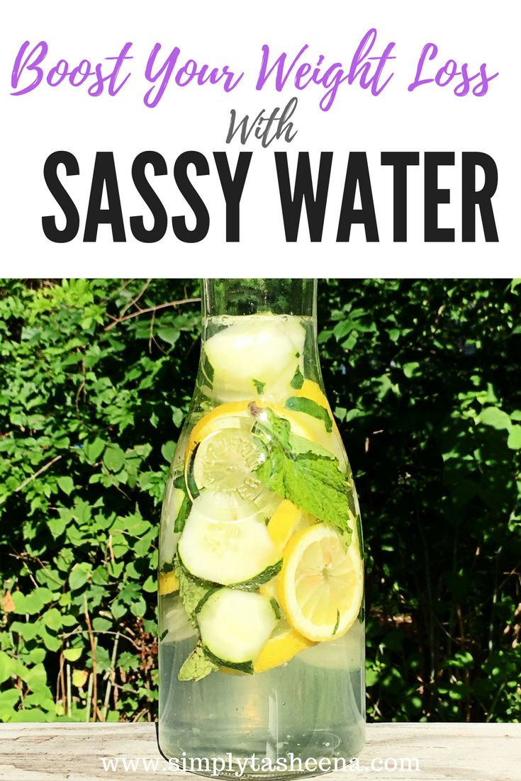 a pitcher filled with lemons and cucumbers on top of a wooden table