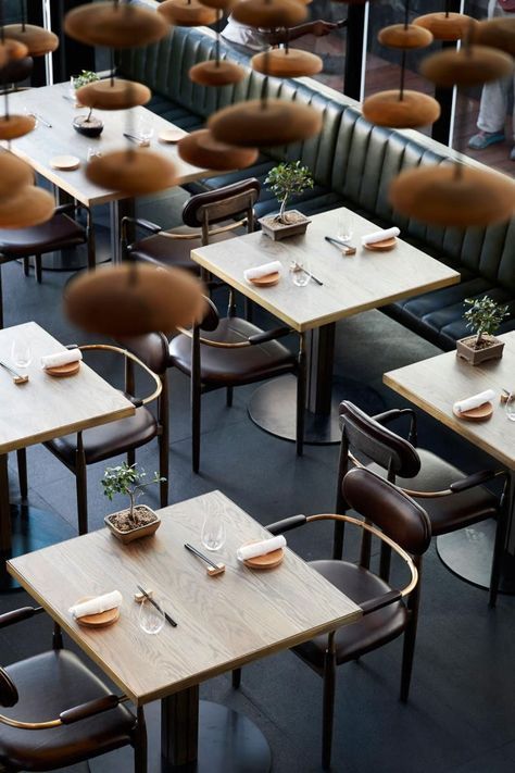 an empty restaurant with tables and chairs covered in brown umbrellas, is seen from above