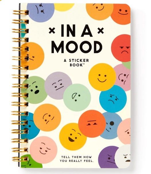 an in a mood notebook with smiley faces on the front and back cover, next to a pen