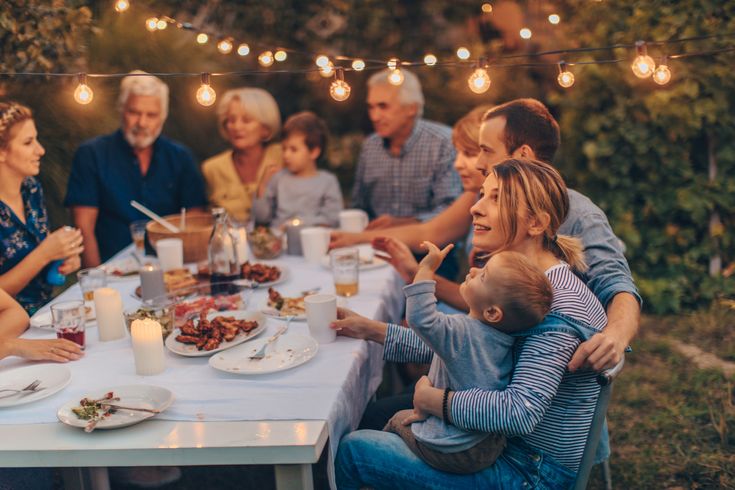 a group of people sitting around a table with food