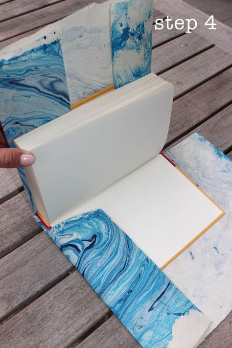 an open book sitting on top of a wooden table covered in blue and white paper