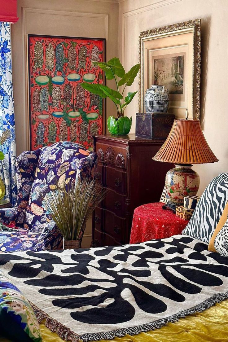 a bedroom with an animal print bed spread and colorful chairs in front of the window