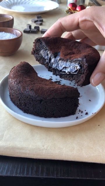 a person holding a piece of chocolate cake on a plate