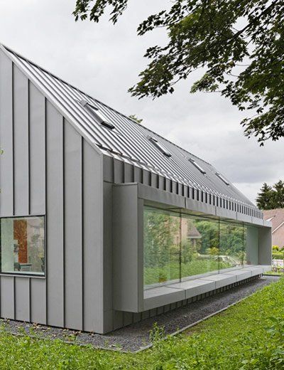 a small house with a metal roof and windows on the outside, surrounded by green grass