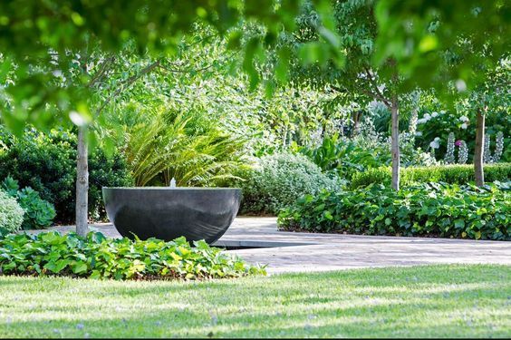 a large black bowl sitting in the middle of a lush green park