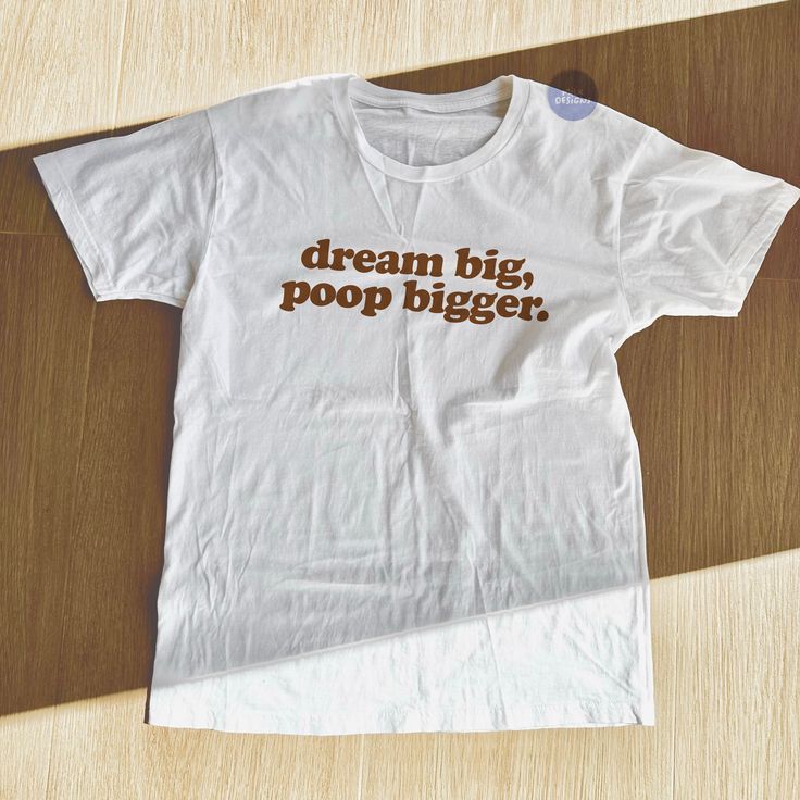 a white t - shirt with the words dream big poop bigger printed on it