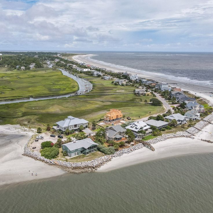 an aerial view of houses on the beach and in the water near some sand dunes