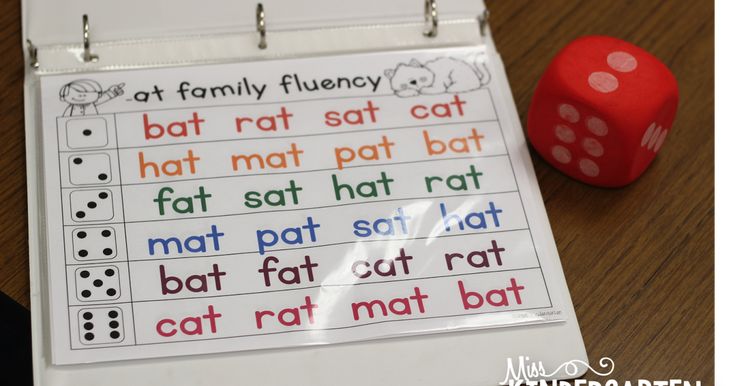 a red dice sitting on top of a wooden table next to a white board with words that read at family flueny