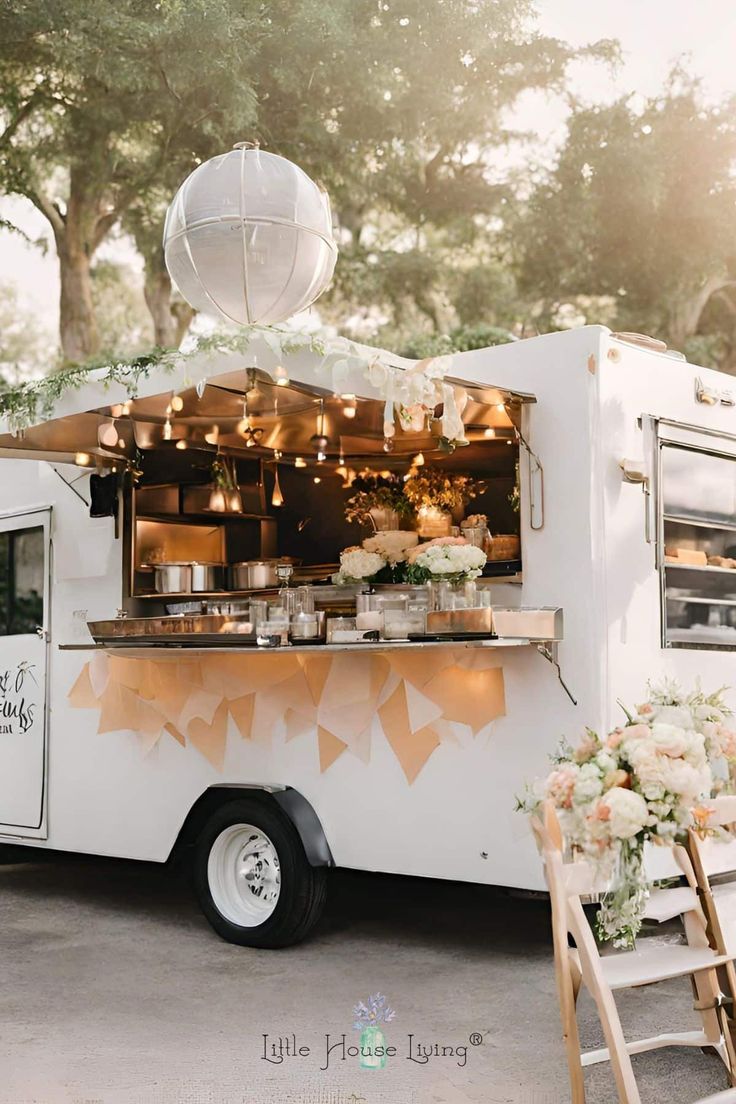 the food truck is decorated with white flowers and greenery for an outdoor wedding reception