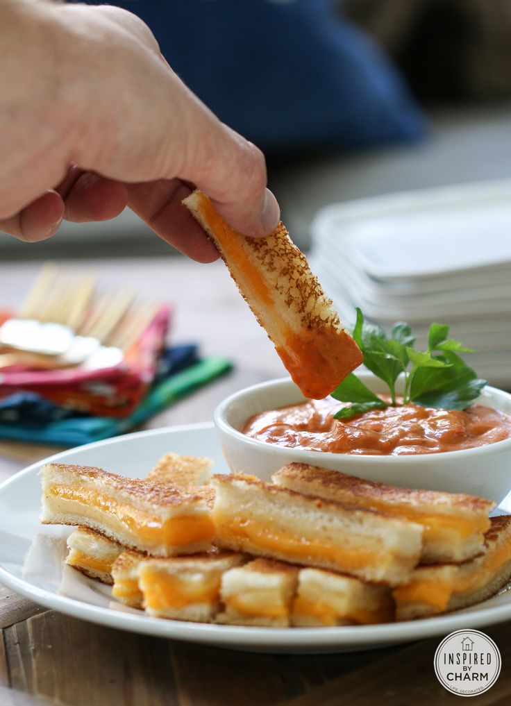 a person dipping something into a bowl of sauce on top of french toast sticks with parsley