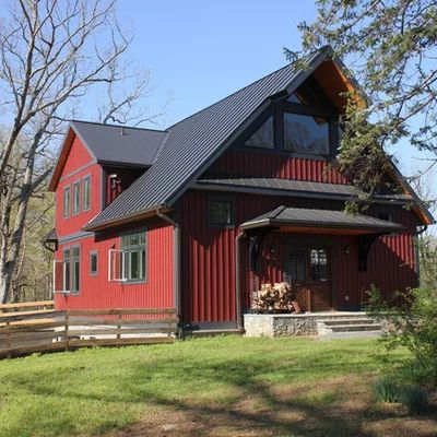 a red house sitting on top of a lush green field