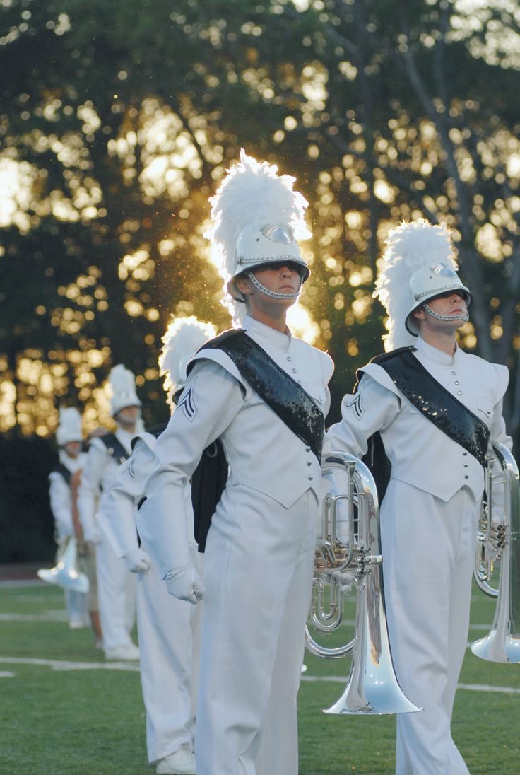 the marching band is dressed in white uniforms