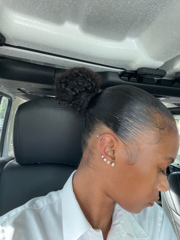 a woman sitting in the back seat of a car with her hair styled into a bun