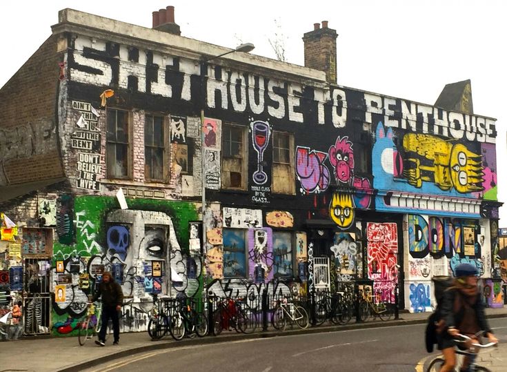 a man riding a bike past a building covered in graffiti