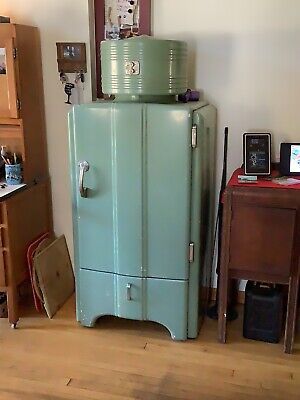 a green refrigerator sitting in the corner of a room