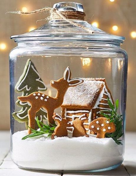 a glass jar filled with snow and decorated gingerbreads