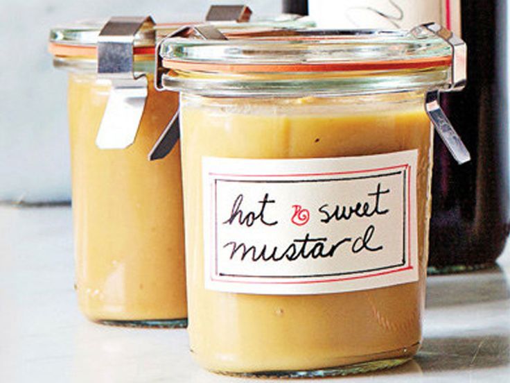 two jars of hot and sweet mustard sitting on a counter