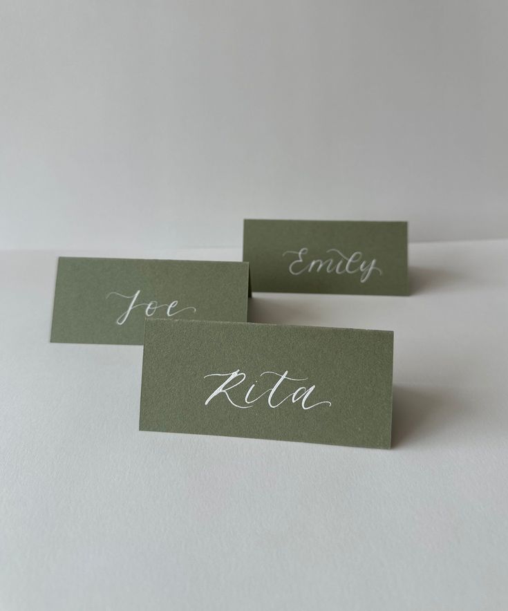 three place cards with the names of two people on them, one is green and the other is white