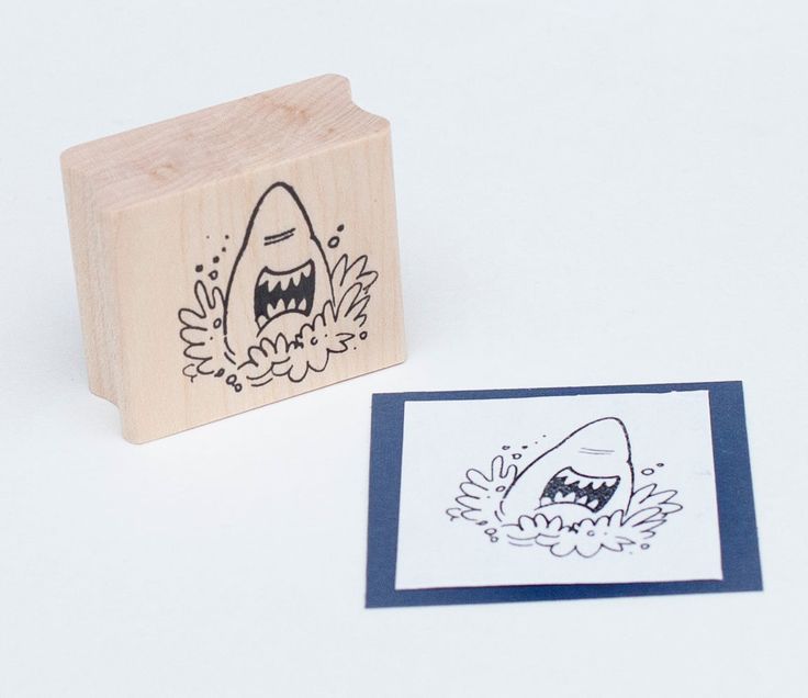 a rubber stamp with a drawing of a shark on it's face and an envelope