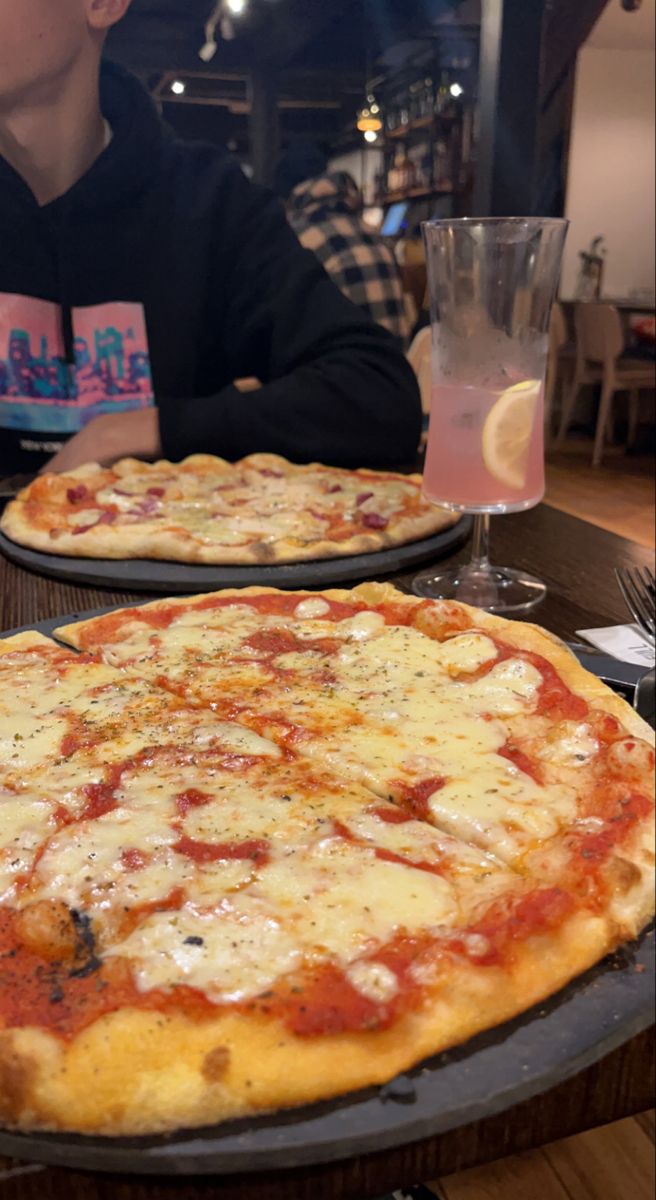 two large pizzas sitting on top of pans next to each other in a restaurant