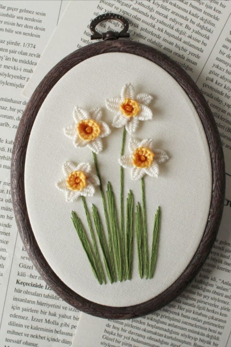 a close up of a embroidery on a piece of paper with flowers in it and grass