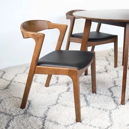 two wooden chairs sitting next to a round table on top of a carpeted floor