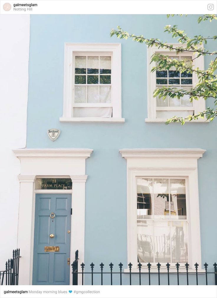 a blue house with white trim and two windows on the front door is seen in this image