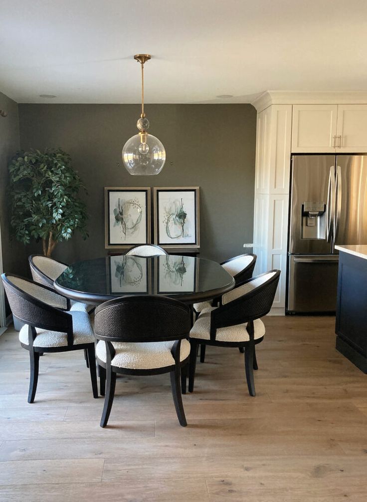 a dining room table with chairs and pictures on the wall