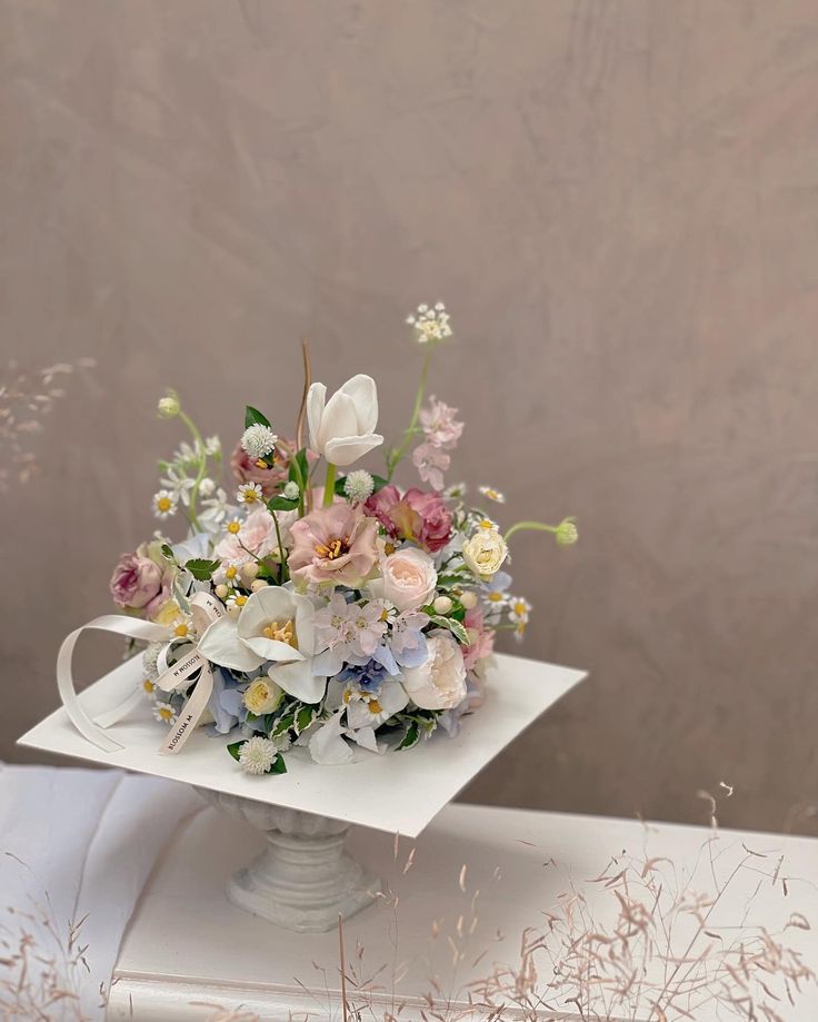 a bouquet of flowers sitting on top of a white box with a ribbon around it