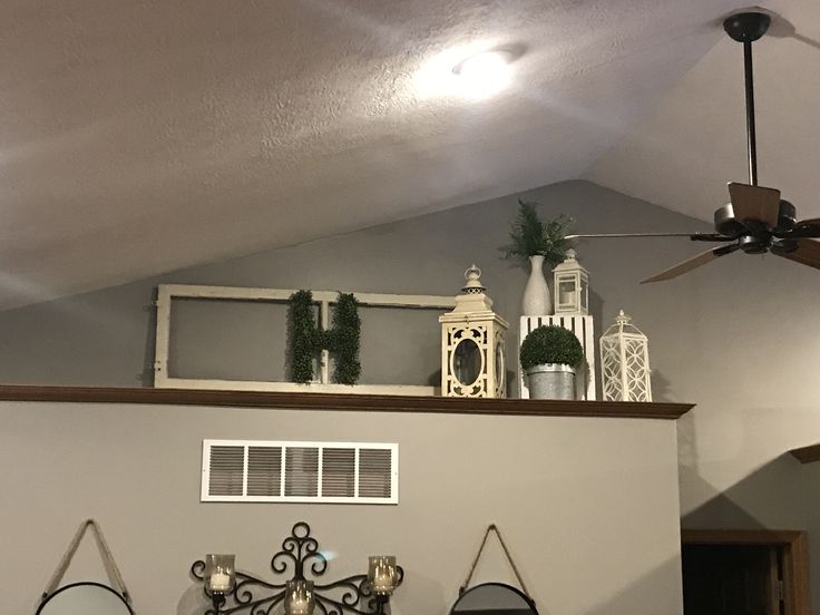 the ceiling fan is hanging on top of the shelf above the mirror and other decorations