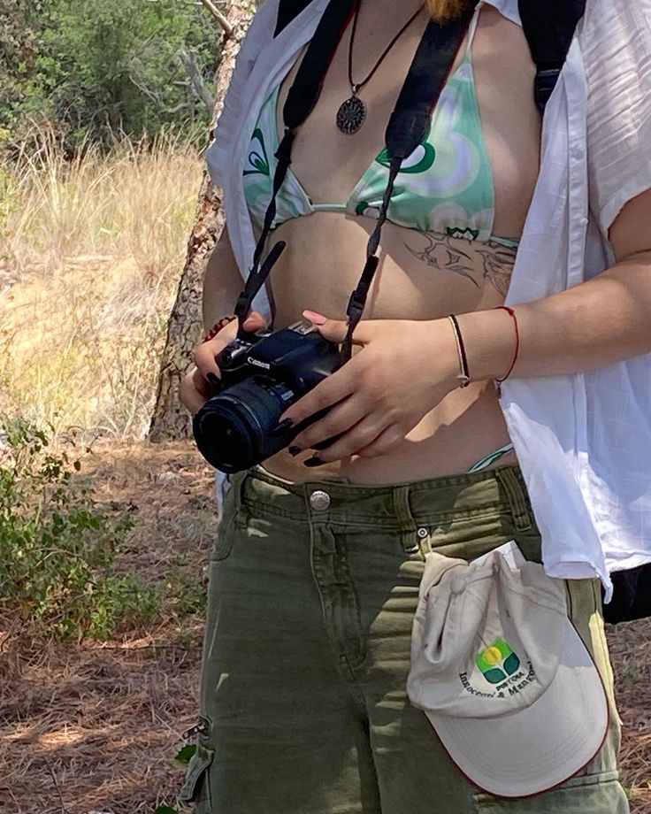 a zoomed in picture of details a green bikini with a white button down and green jorts holding a camera Khaki Jorts Outfit, Green Jorts Outfit Idea, Jorts Outfit Idea, Jorts Outfit, Outfit Ideas Vacation, Green Outfit, Summer Outfit Ideas, Dream Style, Outfit Idea