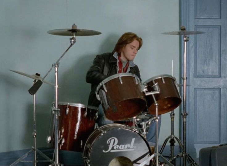 a young man is playing drums in front of his drum set and another drummer behind him