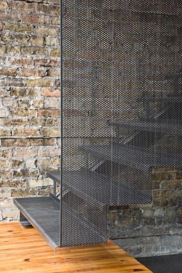 a metal screen sitting on top of a wooden table next to a brick wall and floor