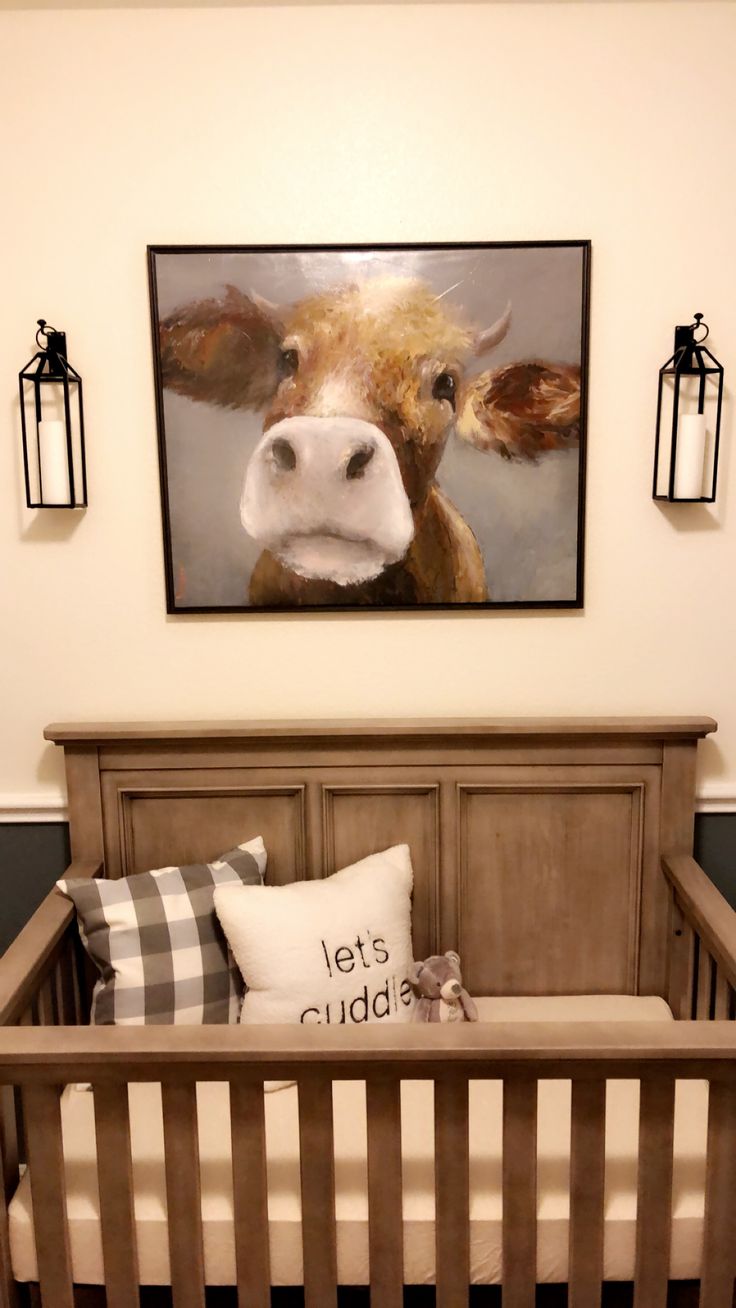 a baby crib with a cow painting on the wall