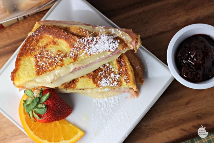 two pieces of french toast sitting on top of a white plate next to an orange slice