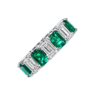 an emerald and diamond ring with baguettes on the sides, set in 18k white gold