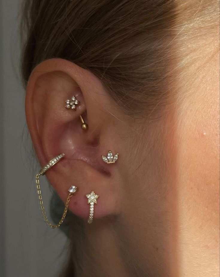 a woman with three different ear piercings on her left ear and one is wearing a cross