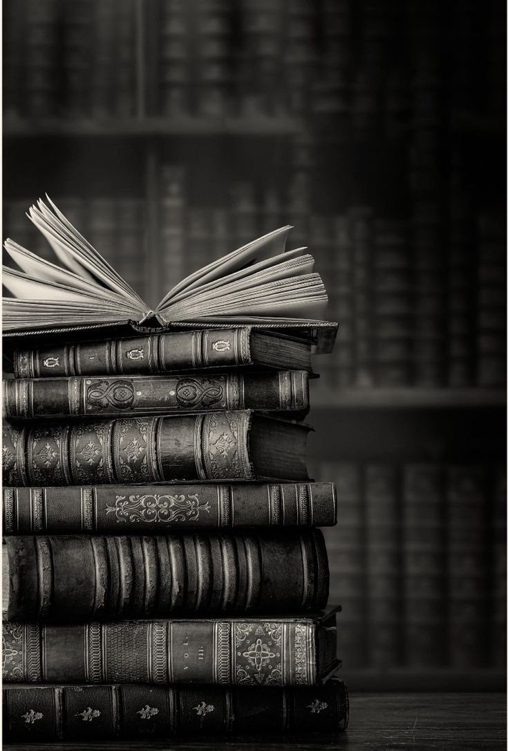 a stack of books sitting on top of each other in front of a book shelf