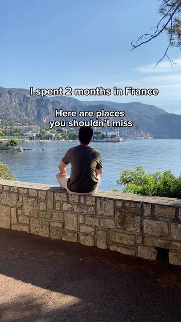 a man sitting on a stone wall looking out over the water with a quote above him