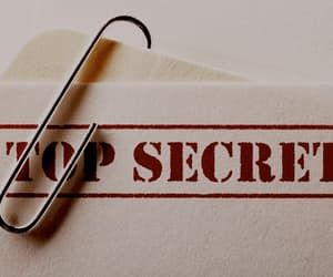 a close up of a paper clip on top of a piece of paper with the word top secret printed on it