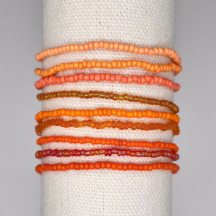 a stack of bracelets with orange and red beads on top of each other in different colors